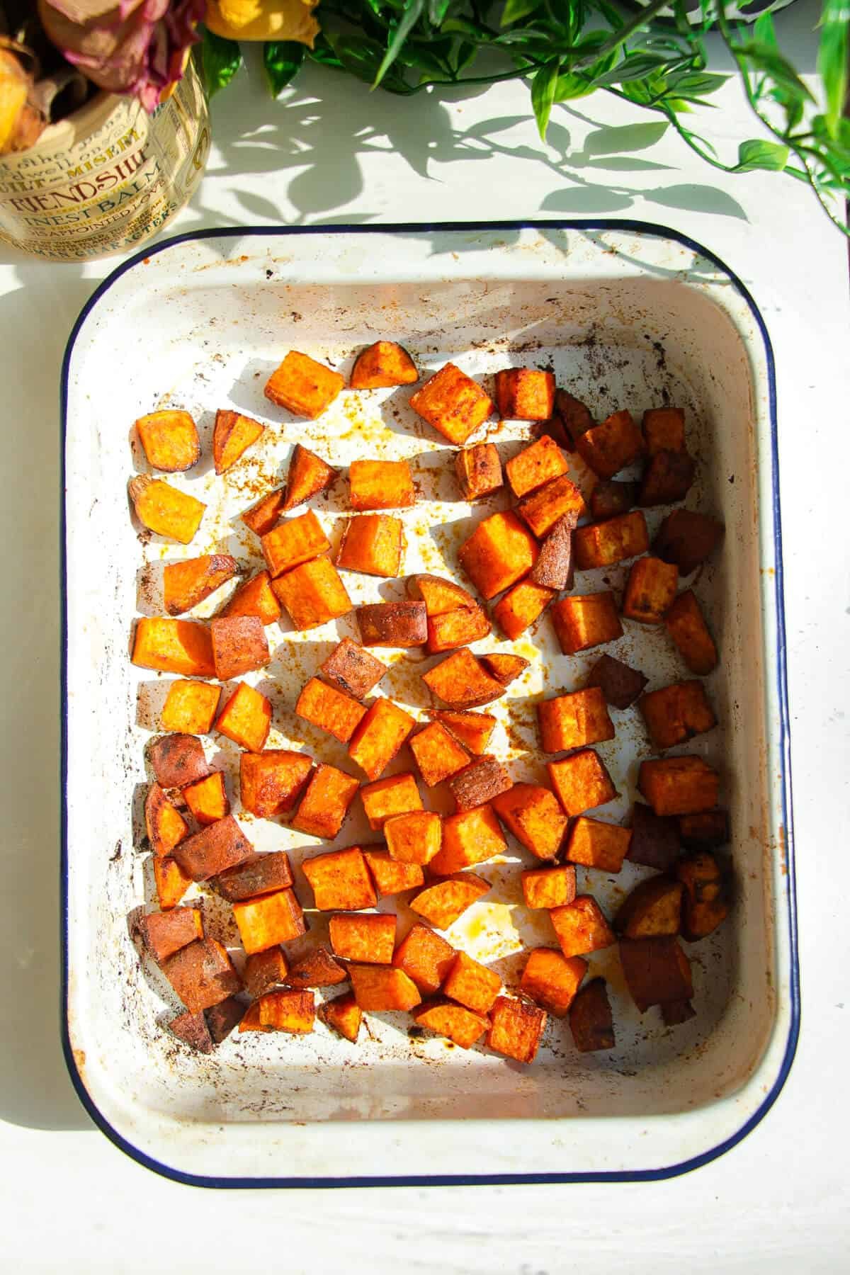 Cooked diced sweet potato in a white oven tray.