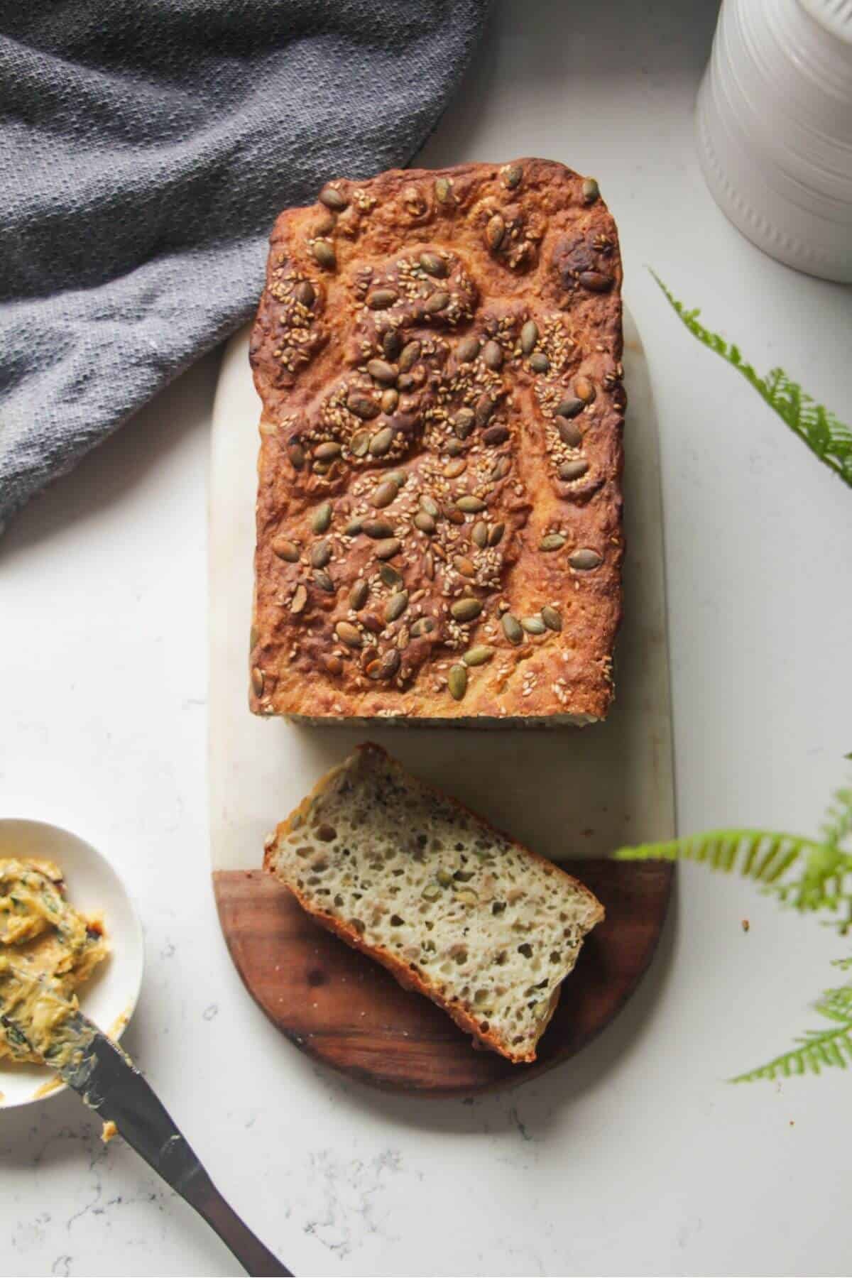 Vogel's style bread on a marble and wooden board, with 1 slices taken out of it.