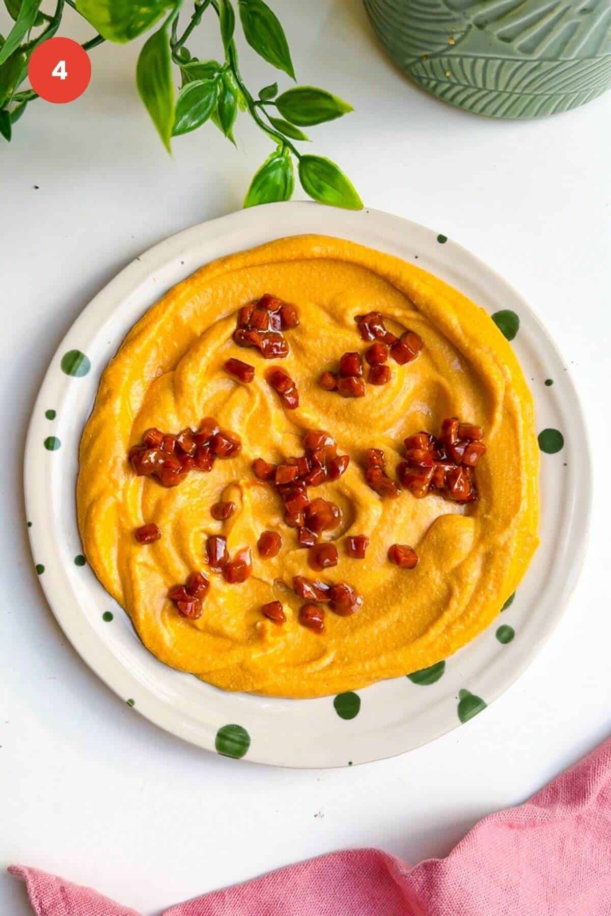 Chorizo on top of butternut squash feta dip on plate.
