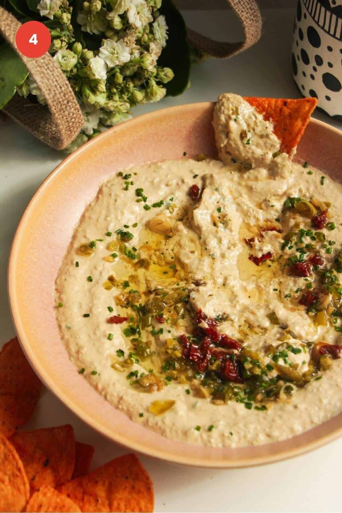 Tortilla chip in whipped cottage cheese dip in a serving bowl.