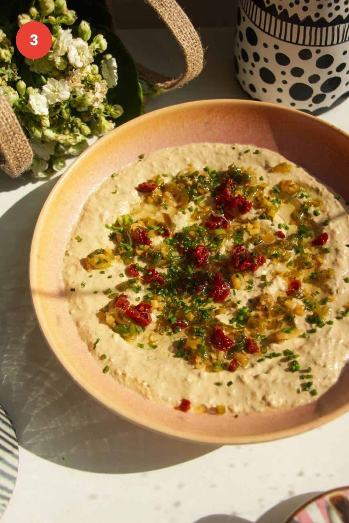 Cottage cheese dip topped with jalapenos and sundried tomatoes in a bowl.