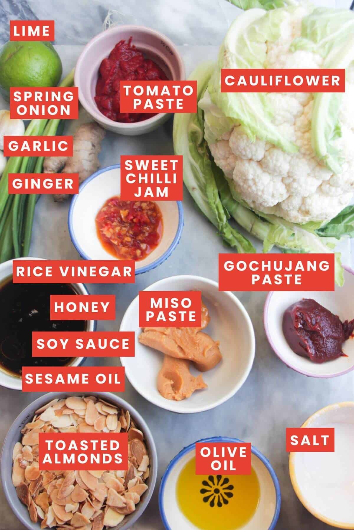 Ingredients for whole roasted cauliflower laid out on a grey marble background and labelled.