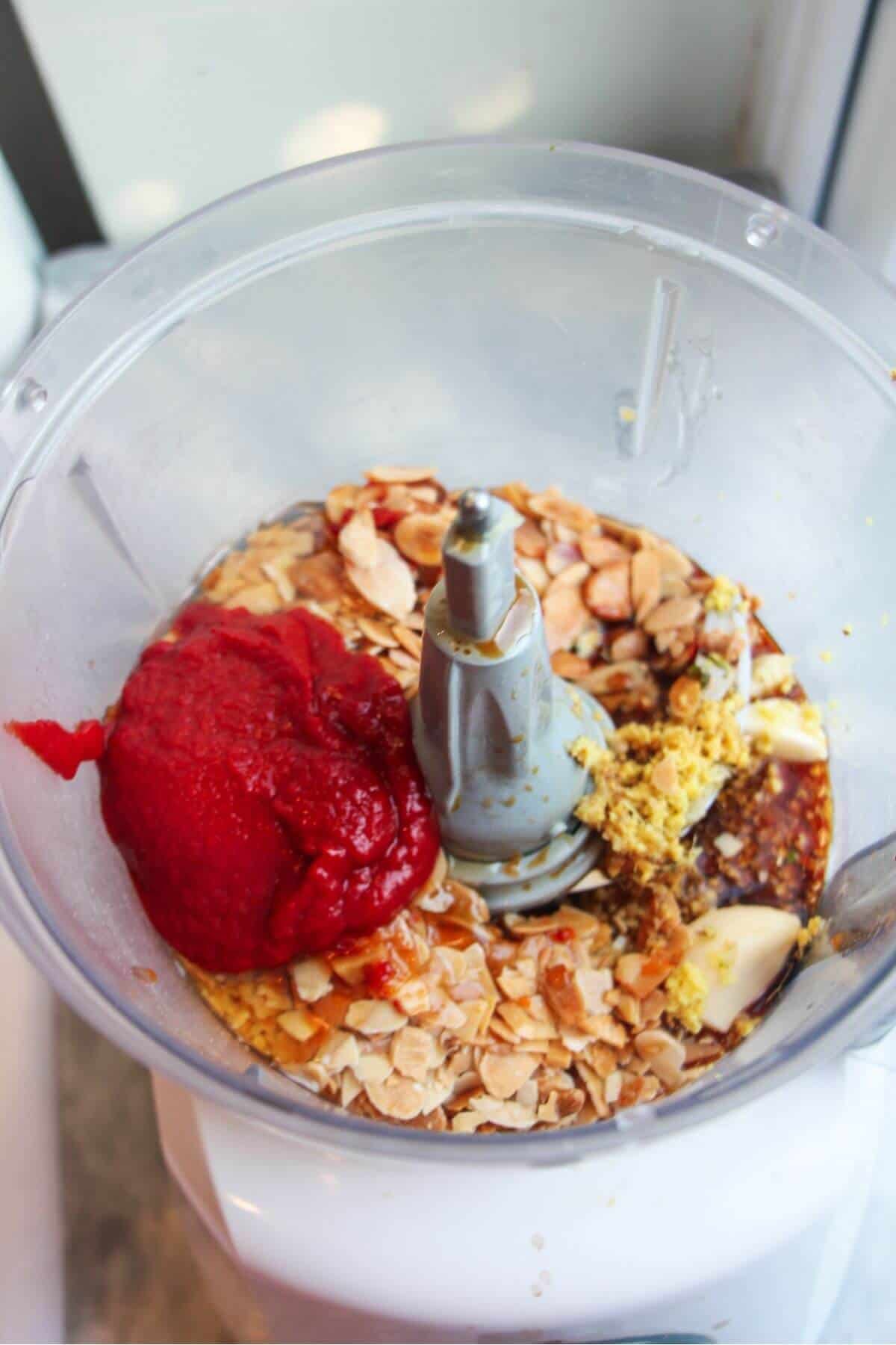 Ingredients for Asian tomato pesto in the bowl of a food processor.