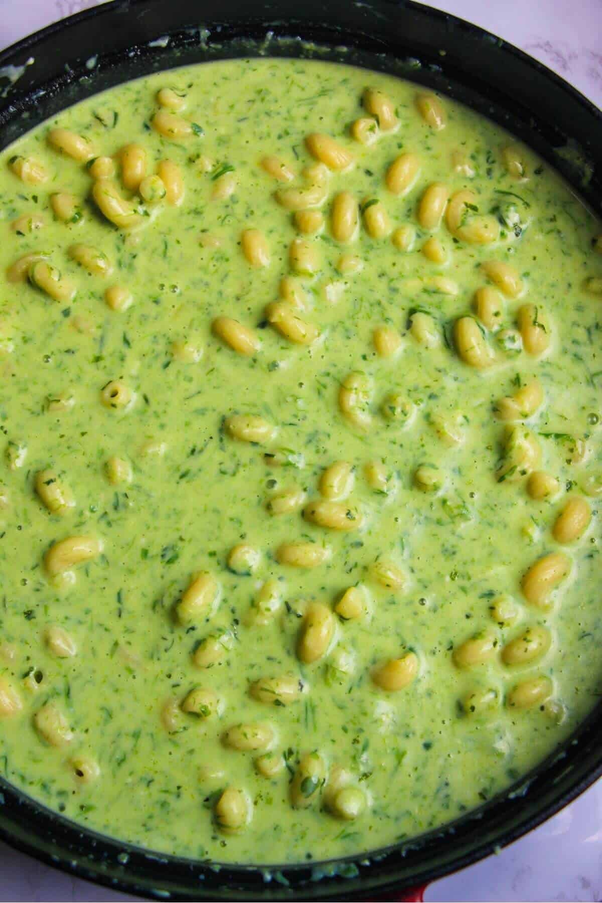 Pasta mixed through wild garlic cheese bechamel sauce in a large pan.