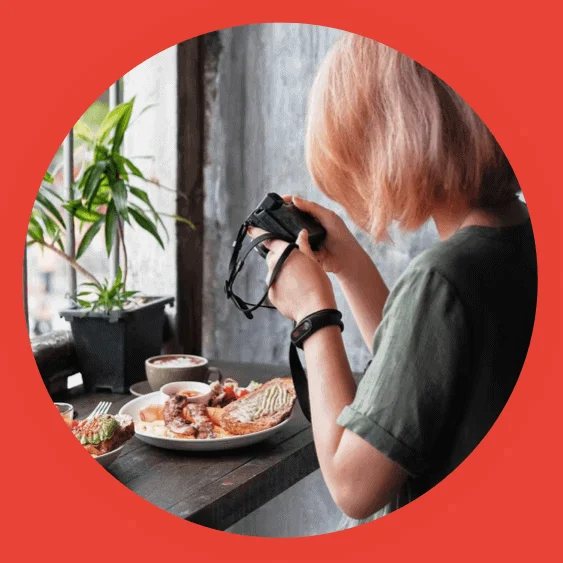 A girl taking a photo of food, holding a camera.