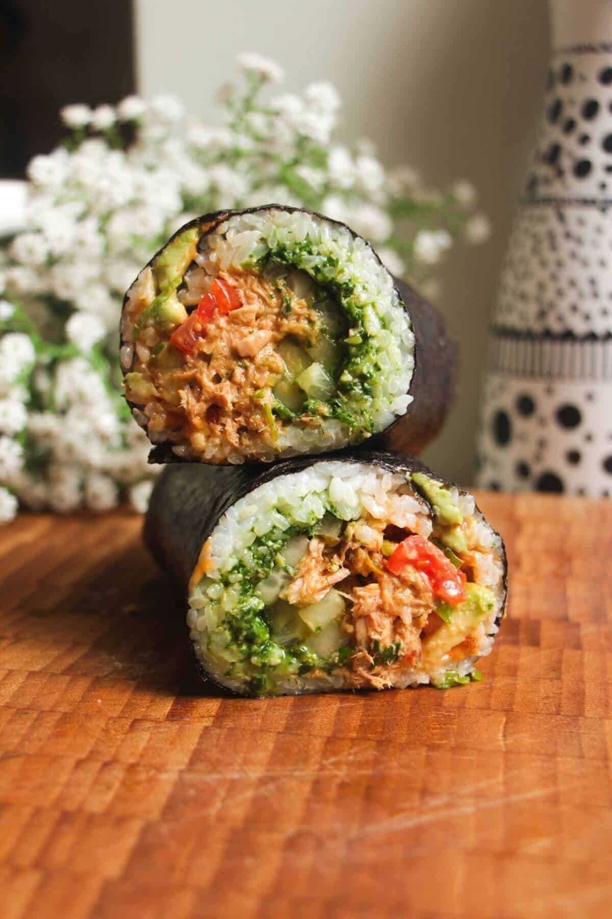 Sliced tuna sushi burrito on top of eachother on a wooden board.