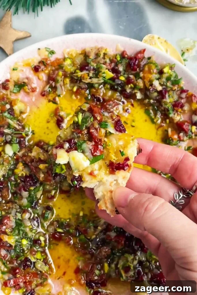 Gourmet Holiday Bread Dipping Blend 7 A hand dipping a piece of fresh bread into the festive dipping oil.