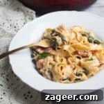 Close up of a bowl of creamy mushroom pasta, with a fork in it.