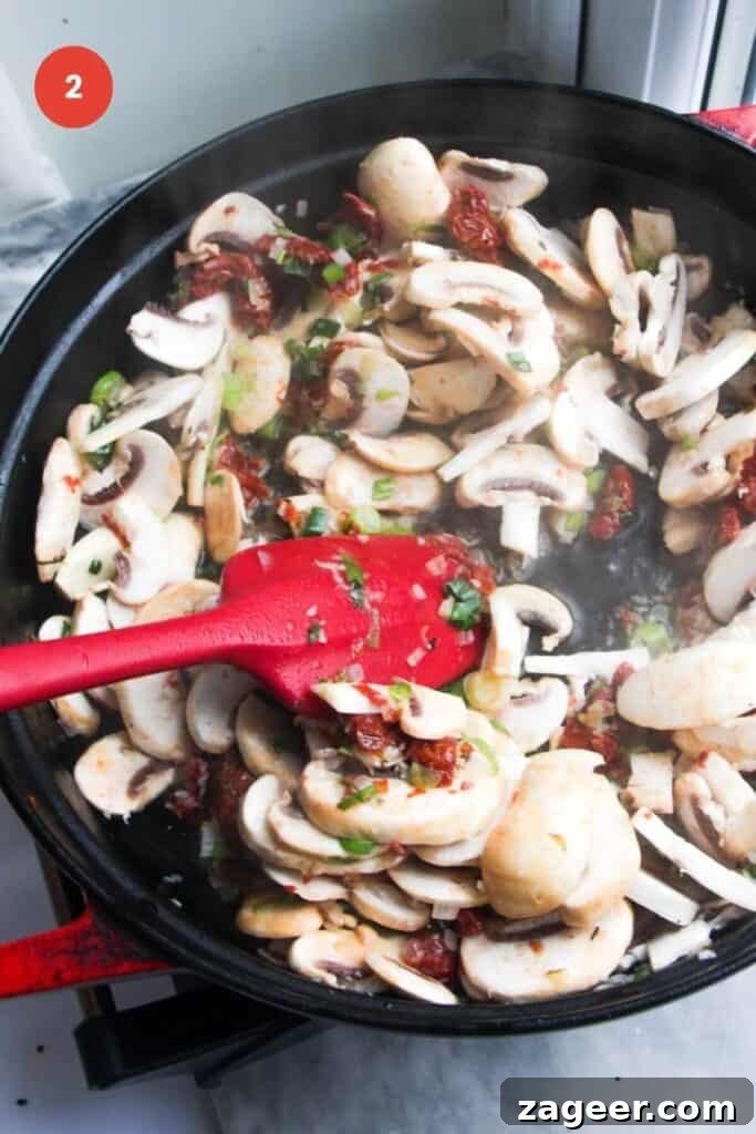 Creamy Miso Mushroom Fettuccine Alfredo 5 Thinly sliced mushrooms being stirred into the sautéed aromatics in a large pan, beginning to release their moisture.