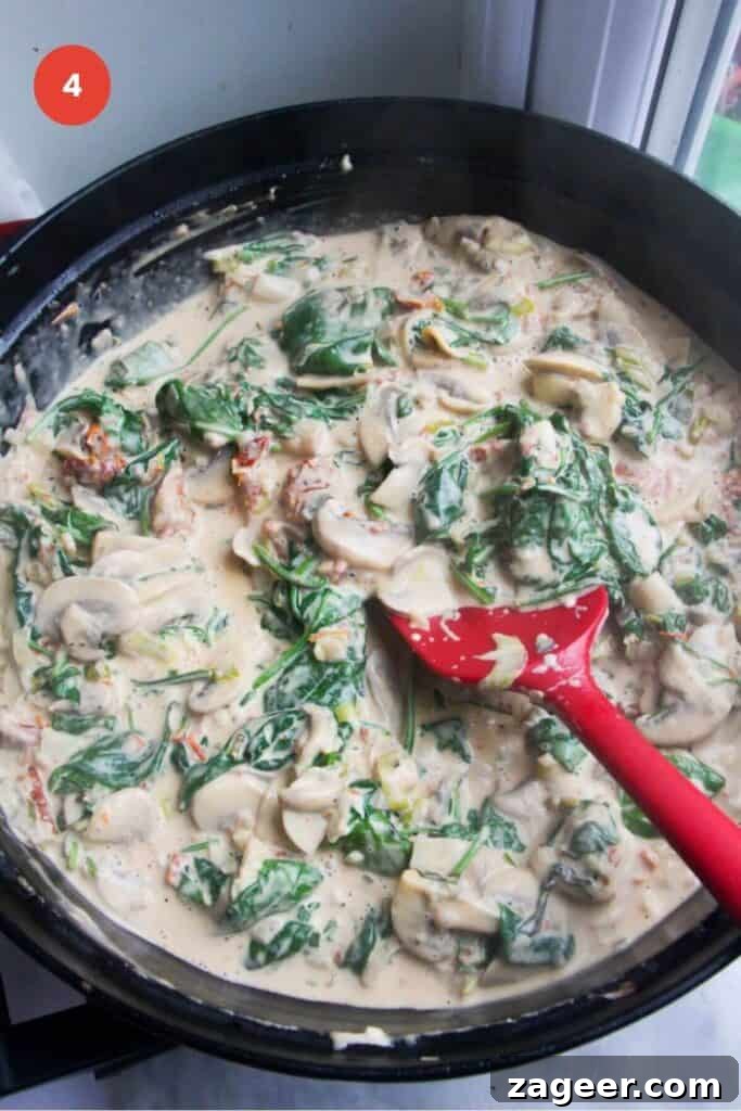 Creamy Miso Mushroom Fettuccine Alfredo 7 Fresh spinach leaves being stirred into the creamy mushroom sauce in a large pan, wilting down beautifully.