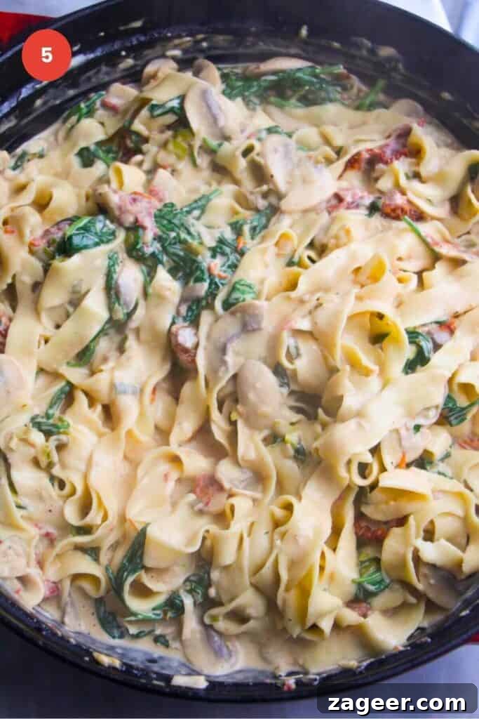 Creamy Miso Mushroom Fettuccine Alfredo 8 Perfectly cooked fettuccine being tossed through the creamy mushroom Alfredo sauce in a pan, ensuring every strand is coated.
