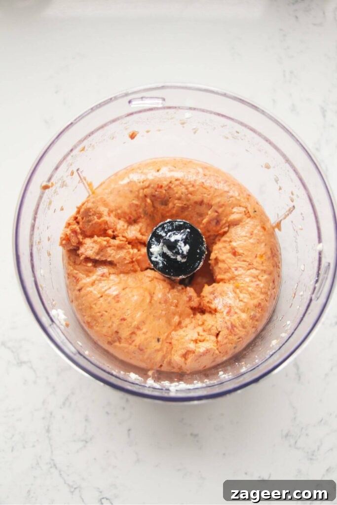 Instant Sun-Kissed Feta Dip 5 Blended sundried tomato feta dip in a small food chopper, showing a creamy, vibrant orange texture.