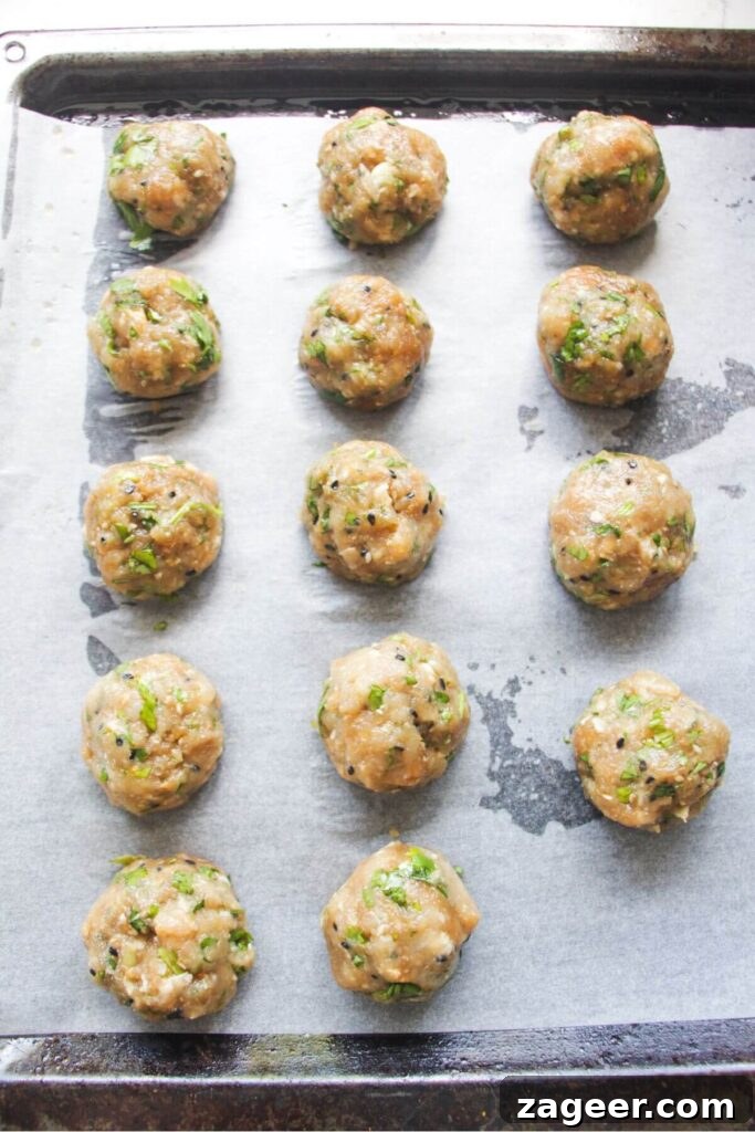 Sticky Gochujang Chicken Meatballs 5 Raw chicken meatballs neatly arranged on a lined oven tray, ready for baking.