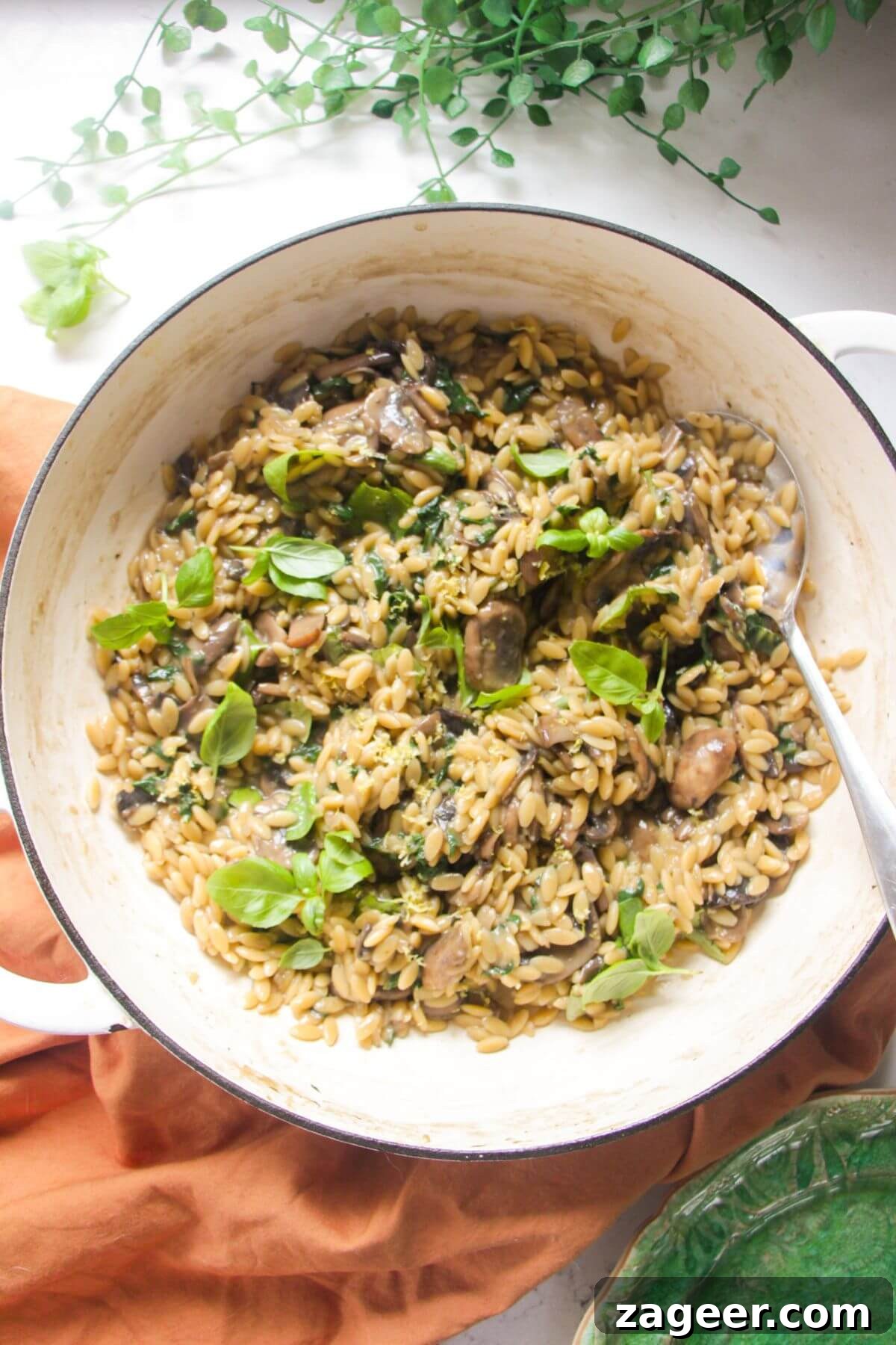 Velvety One-Pot Mushroom Orzo 2 Mushroom orzo in a large white skillet with a large silver spoon.