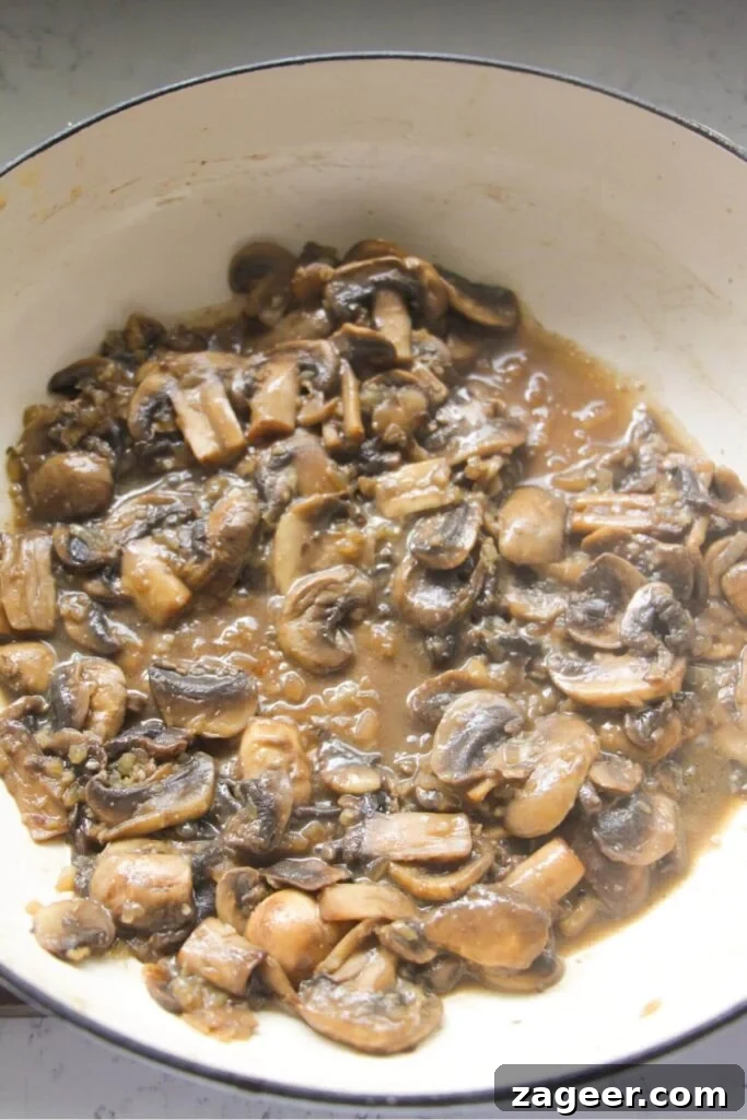Velvety One-Pot Mushroom Orzo 5 Sliced mushrooms with white wine in a large white skillet.