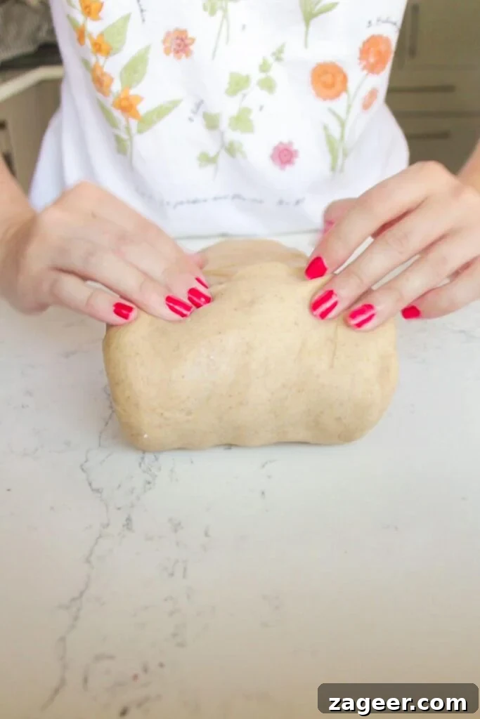 Easter Mini Egg Chocolate Hot Cross Buns 8 Rolling up mini egg hot cross bun dough on a white marble background.