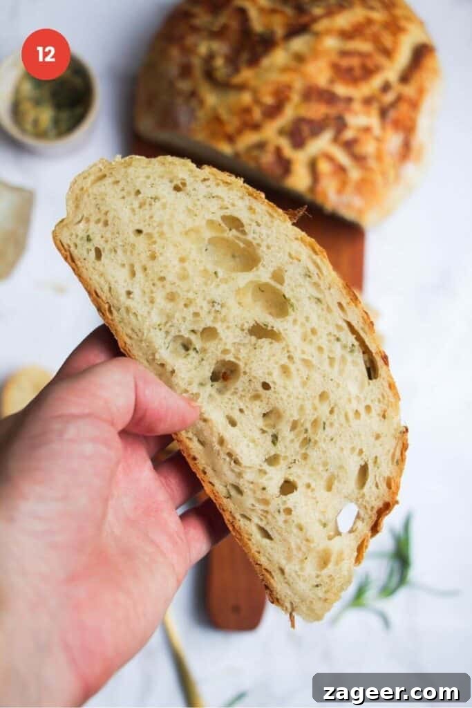 Artisan Style Rosemary Parmesan Bread Done Easy 15 Hand holding slice of rosemary parmesan bread.