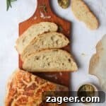 Artisan Style Rosemary Parmesan Bread Done Easy 17 3 slices of bread on a small wooden board with the rest of the loaf and garlic butter in the background.