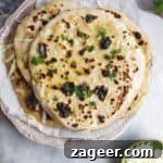 A pile of cheese naan on a small pink plate with a small bowl of grated cheese and butter on the side.