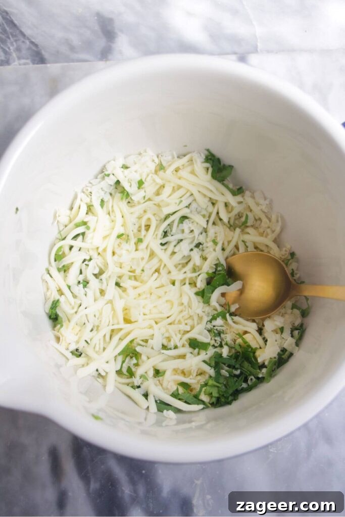 Effortless Two Ingredient Cheesy Naan 6 Grated cheese and chopped fresh green herbs being mixed together in a small white bowl, forming the delicious filling for the naan.