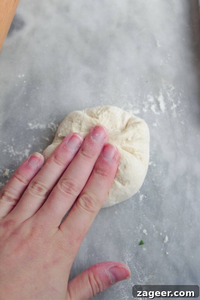 Effortless Two Ingredient Cheesy Naan 8 A hand pressing down to carefully seal the edges of the naan dough, encasing the cheese filling securely.