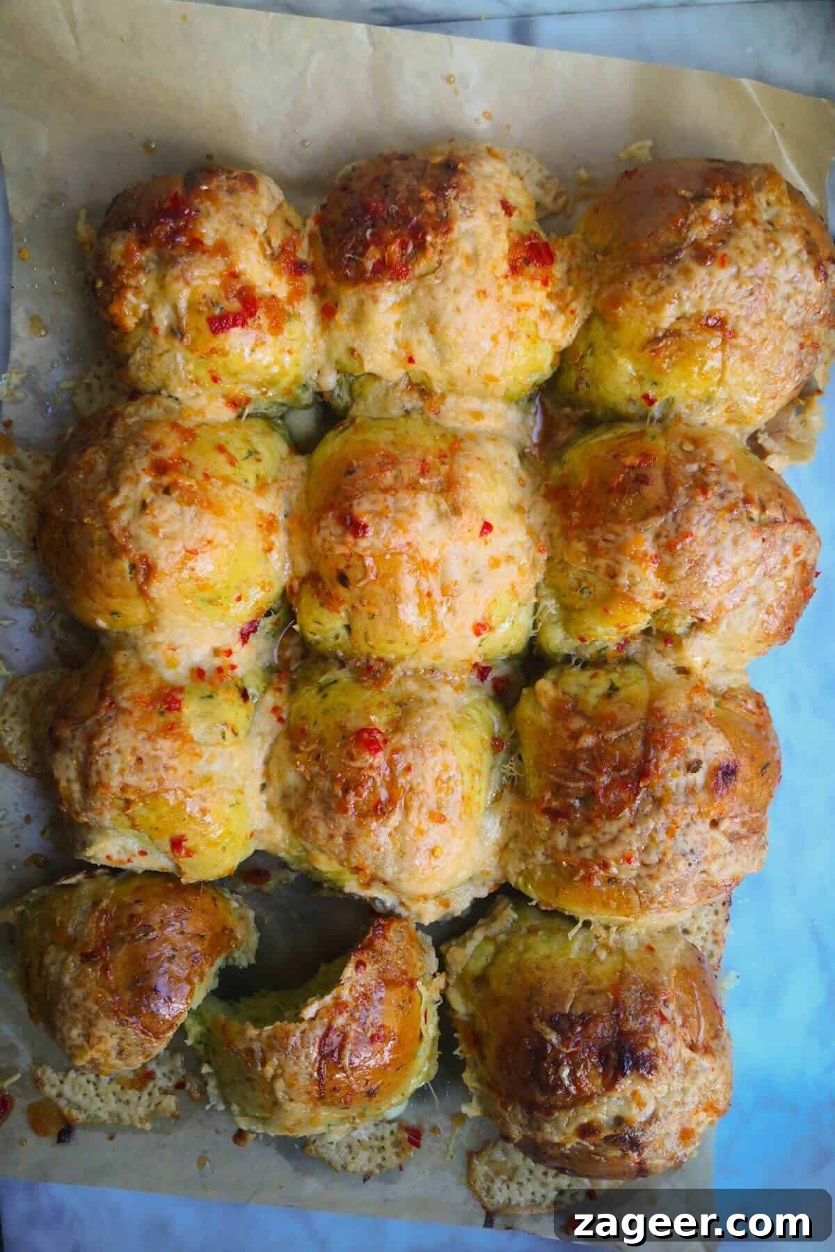 Wild Garlic & Cheddar Savory Hot Cross Buns 2 A baker's dozen of golden-brown wild garlic hot cross buns, adorned with white béchamel crosses, are arranged on a parchment-lined baking tray, ready to be enjoyed.