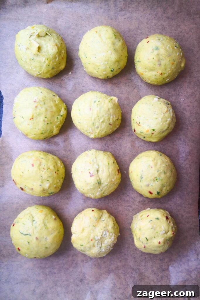 Wild Garlic & Cheddar Savory Hot Cross Buns 10 A dozen perfectly shaped wild garlic hot cross bun dough balls are neatly arranged on a lined baking tray, ready for their second rise.