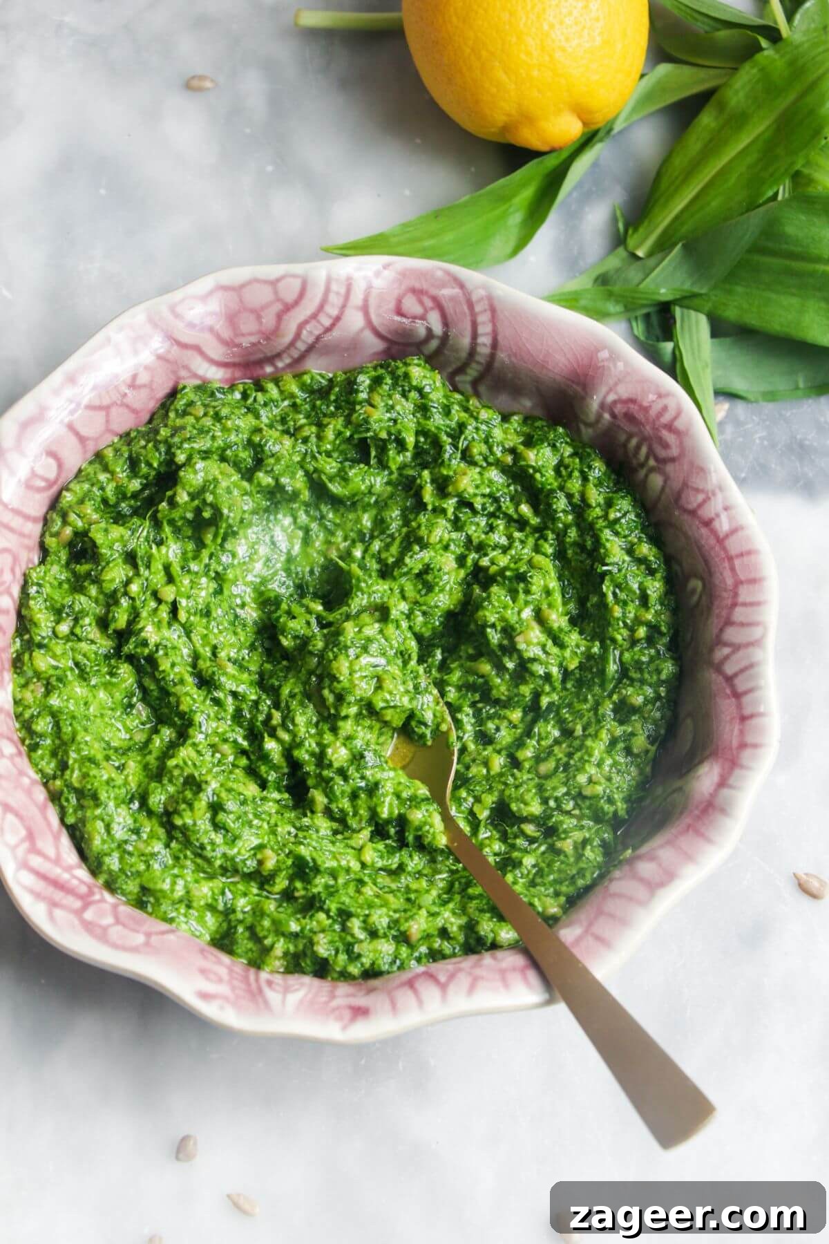 Wild Garlic Pesto in 5 Minutes 2 Bright green wild garlic pesto in a small pink bowl on a grey marble background.