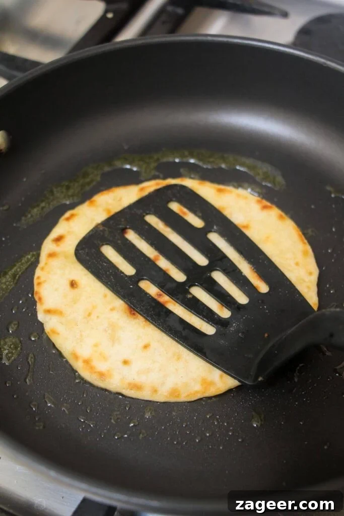 Big Mac Smash Burger Taco Fusion 6 A black spatula firmly pressing a beef-laden tortilla into a hot black frying pan, ensuring maximum contact for a crispy crust.