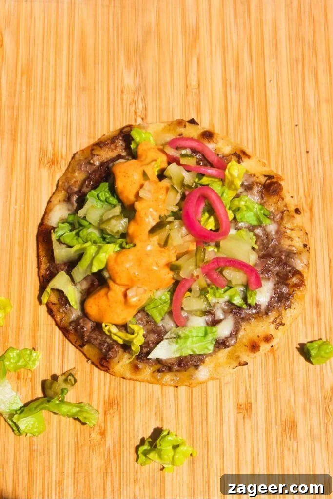 Big Mac Smash Burger Taco Fusion 8 A vibrant Big Mac taco generously loaded with shredded lettuce, finely chopped pickles, and a rich drizzle of Big Mac sauce, layered atop the cheesy beef patty on a tortilla.