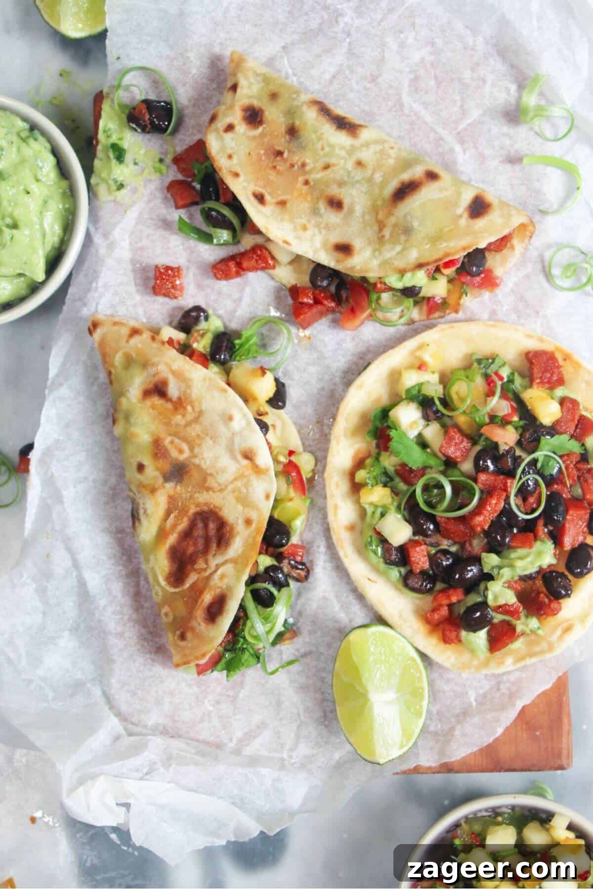 Spicy Chorizo and Black Bean Tacos with Sweet Pineapple Salsa 2 Three perfectly assembled chorizo black bean tacos, garnished with fresh cilantro, served on a baking paper-lined wooden board alongside bowls of creamy whipped avocado and vibrant pineapple salsa.