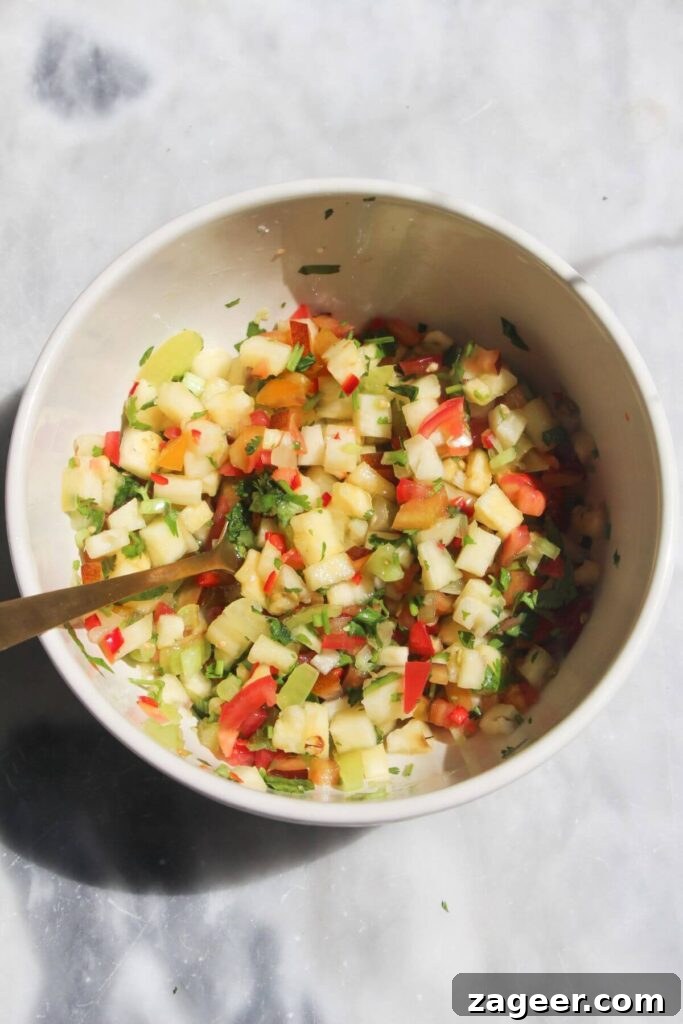 Spicy Chorizo and Black Bean Tacos with Sweet Pineapple Salsa 5 A small white bowl filled with freshly mixed, vibrant pineapple salsa, showcasing its colorful ingredients.