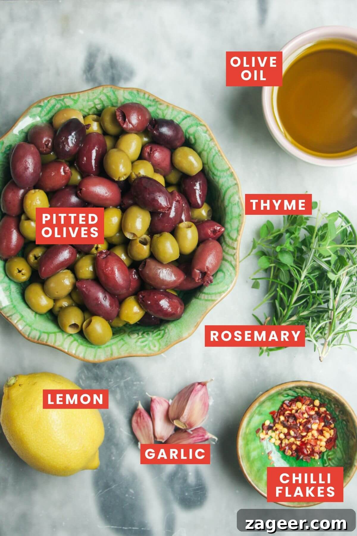 Zesty Olives in Minutes 3 Ingredients for marinated olives laid out on a grey marble background and clearly labelled.