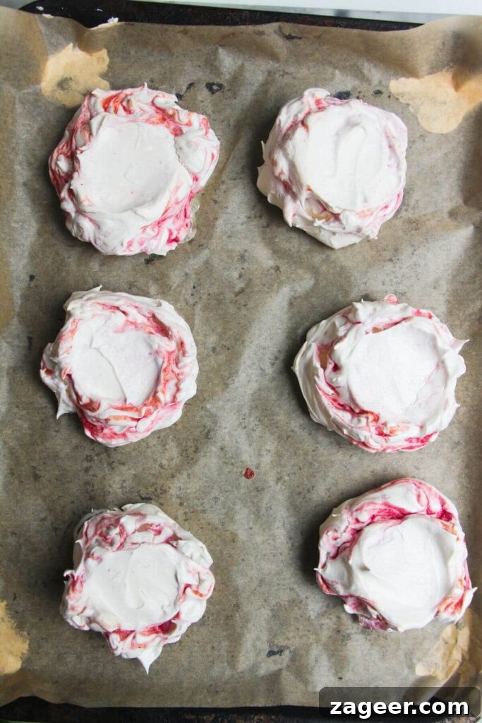 Heavenly Berry Ripple Cheesecake Pavlova Bites 15 6 berry ripple mini pavlovas on a lined baking tray.