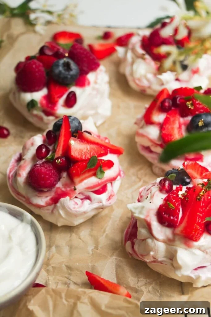 Heavenly Berry Ripple Cheesecake Pavlova Bites 18 Close up of berry topped mini pavlovas on baking paper.