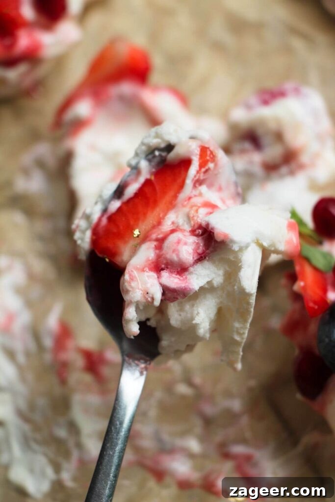 Heavenly Berry Ripple Cheesecake Pavlova Bites 19 Fluffy pavlova on a small spoon.