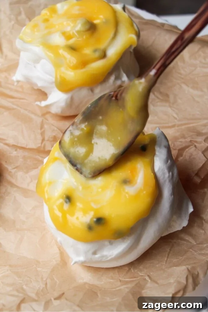 Heavenly Berry Ripple Cheesecake Pavlova Bites 23 Wooden spoon topping mini pavlova with passionfruit curd.