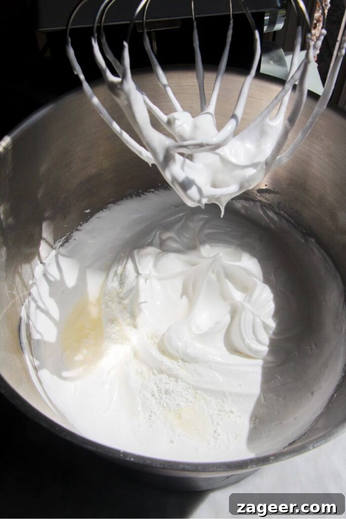 Heavenly Berry Ripple Cheesecake Pavlova Bites 7 Vinegar and cornflour added to whipped meringue in a silver bowl.