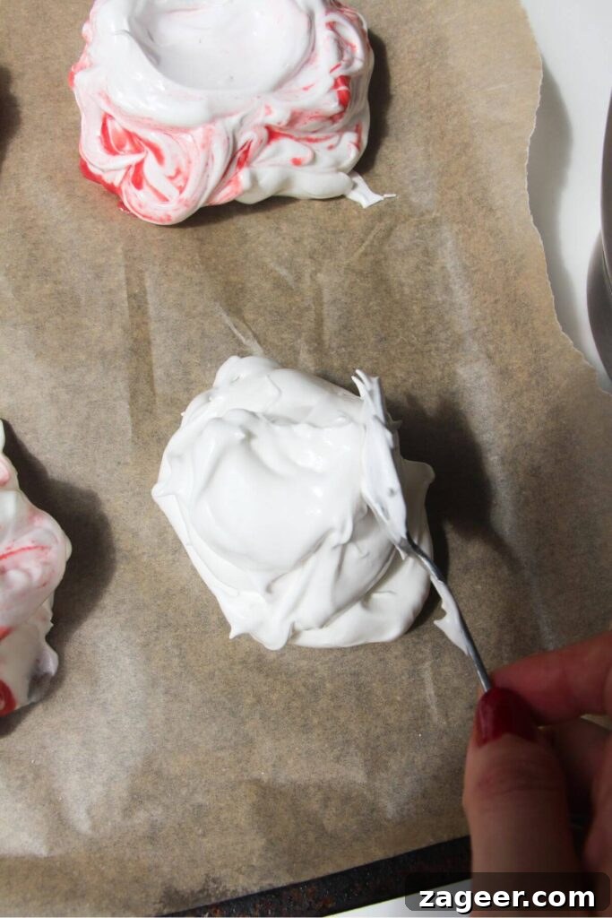 Heavenly Berry Ripple Cheesecake Pavlova Bites 8 Silver spoon dolloping meringue onto lined baking tray.