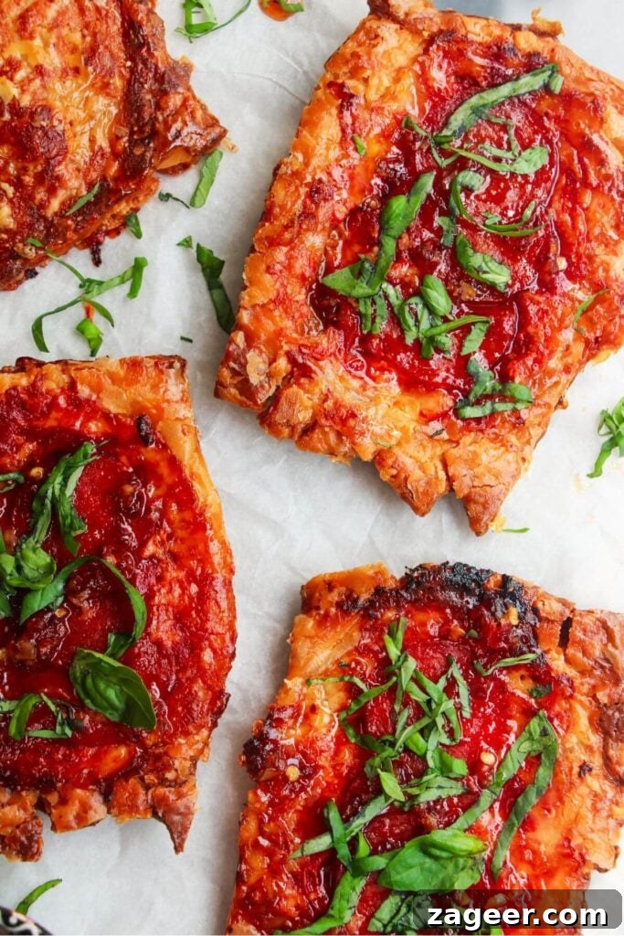 Puff Pastry Pizza Flips 10 A vibrant close-up of three finished upside down puff pastry pizza tarts, highlighting the melted cheese, pepperoni, and fresh basil.