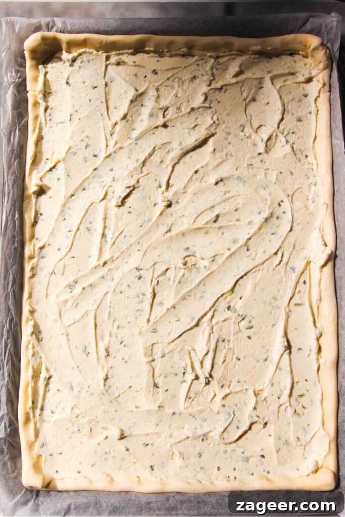 Golden Zucchini Puff Pastry Tart 5 Creamy Boursin cheese mixture expertly spread across the base of a sheet of puff pastry, prepared for the zucchini topping.