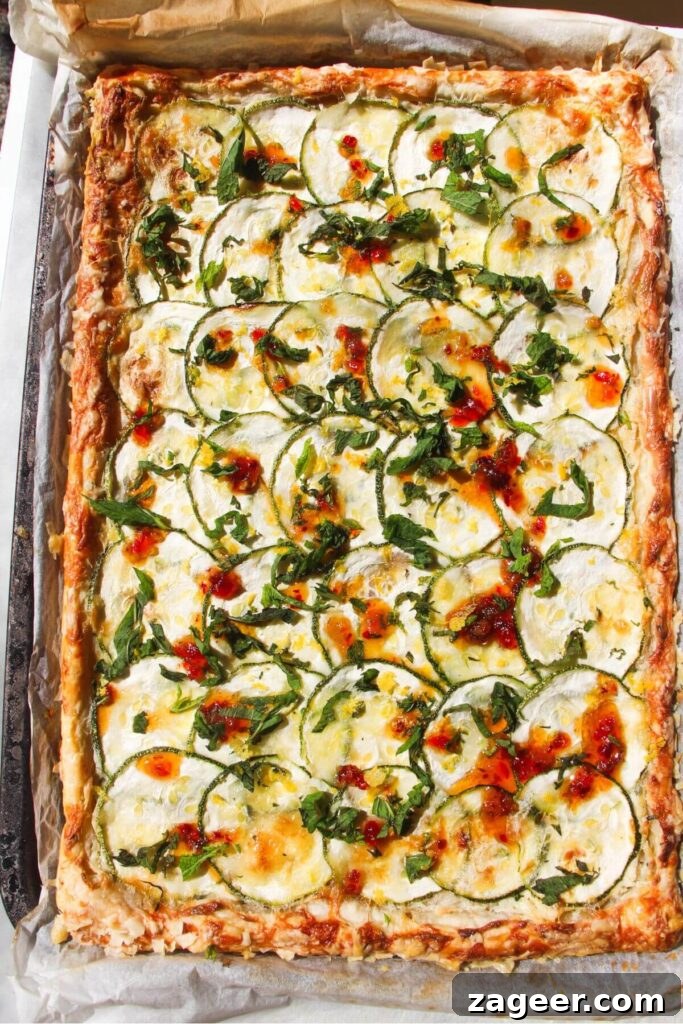 Golden Zucchini Puff Pastry Tart 8 The finished Zucchini Puff Pastry Tart adorned with a glistening drizzle of sweet chilli jam and fresh mint leaves, enhancing its visual appeal.