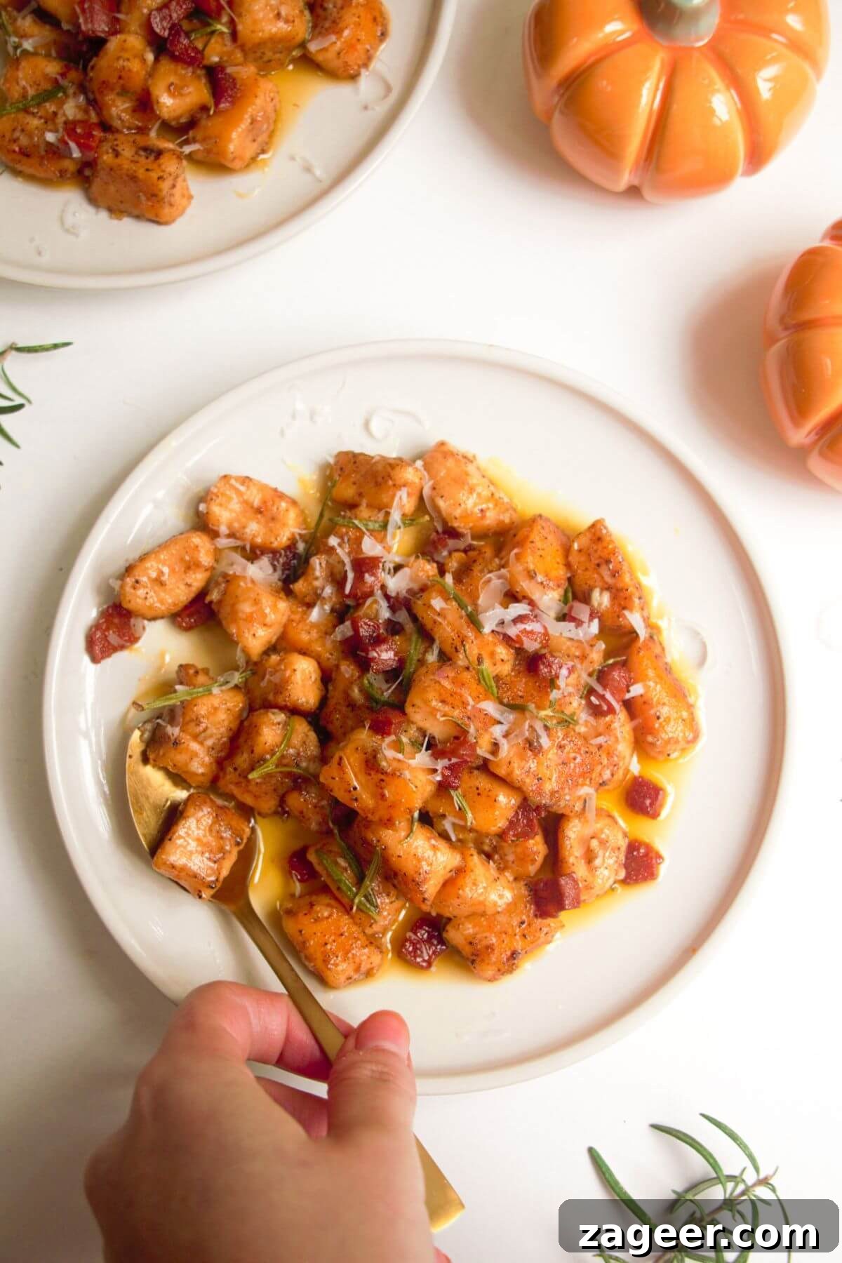 Effortless 5-Ingredient Sweet Potato Gnocchi 2 Sweet potato gnocchi on a small white plate, with a gold spoon.