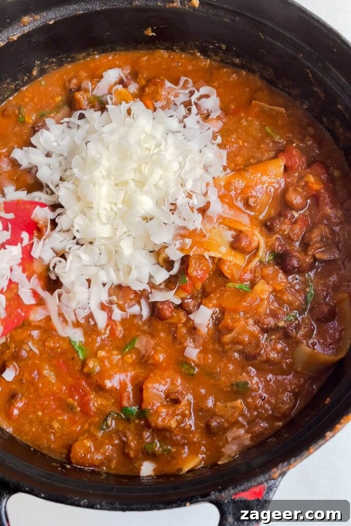 Stealthy Veggie One Pot Lasagna Soup 11 Grated parmesan added to lasagna soup in a large bowl, enriching the taste.