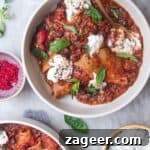 Two bowls of vegetarian lasagna soup, with ricotta on the side.
