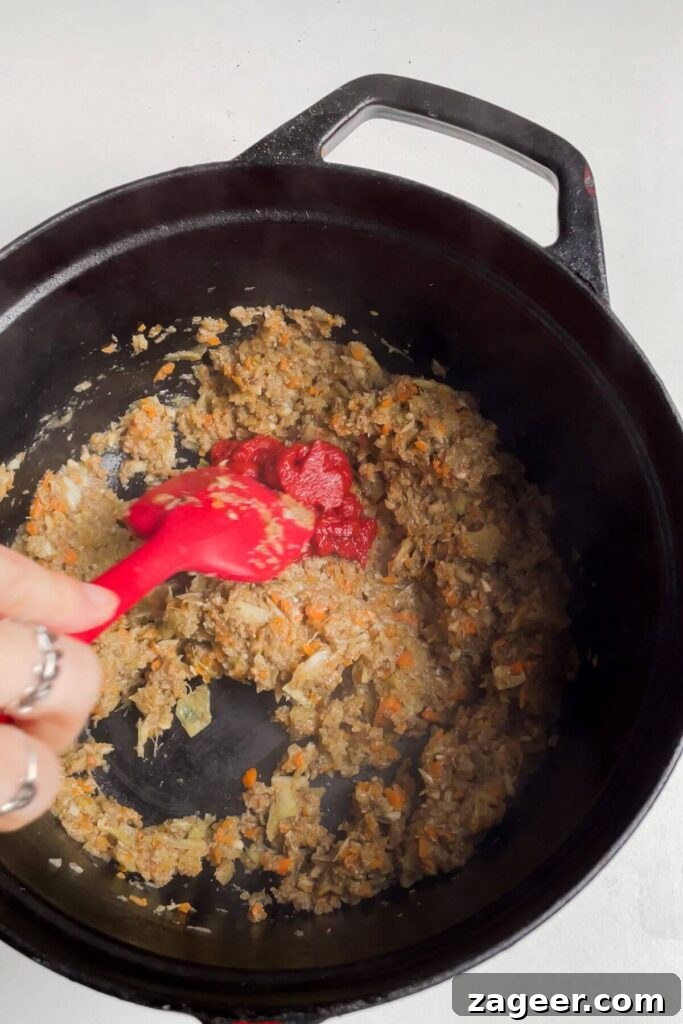 Stealthy Veggie One Pot Lasagna Soup 4 Spatula stirring minced mushroom, garlic, onion, celery and carrot in a large pot, the base of the lasagna soup.