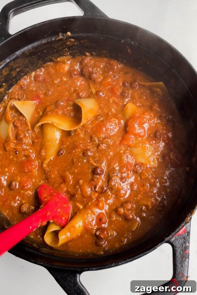Stealthy Veggie One Pot Lasagna Soup 9 Spatula stirring lasagna sheets through soup in a large pot, showing them cooking to al dente.