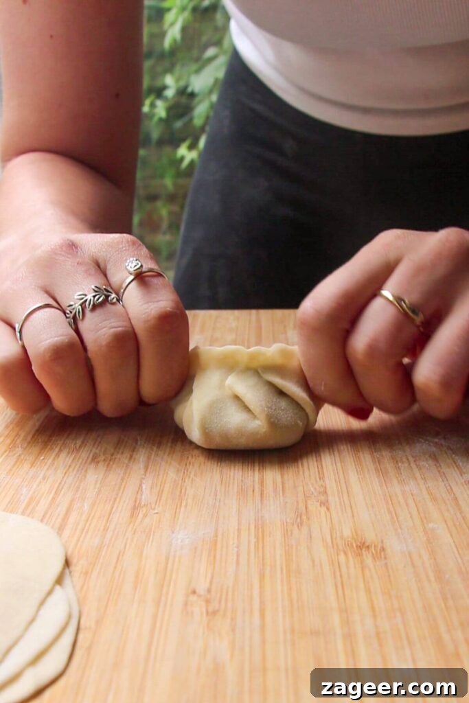 Hands folding dumpling on a wooden board.
