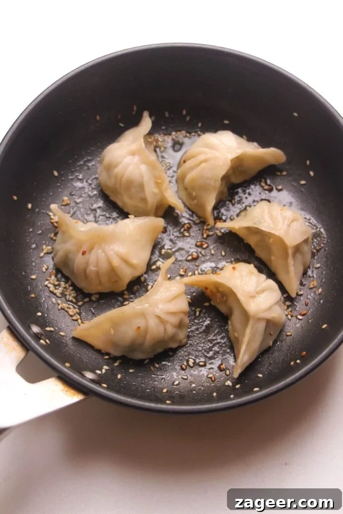 Six pan fried dumplings in a small pan.