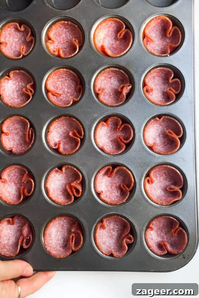 Loaded Antipasto Salami Crisps 4 Individual salami slices pressed into a mini muffin tin, ready for baking.